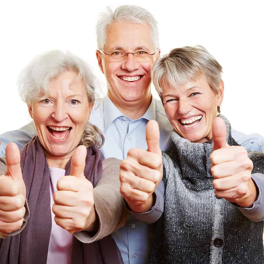 Drei attraktive Senioren halten glücklich ihre Daumen hoch